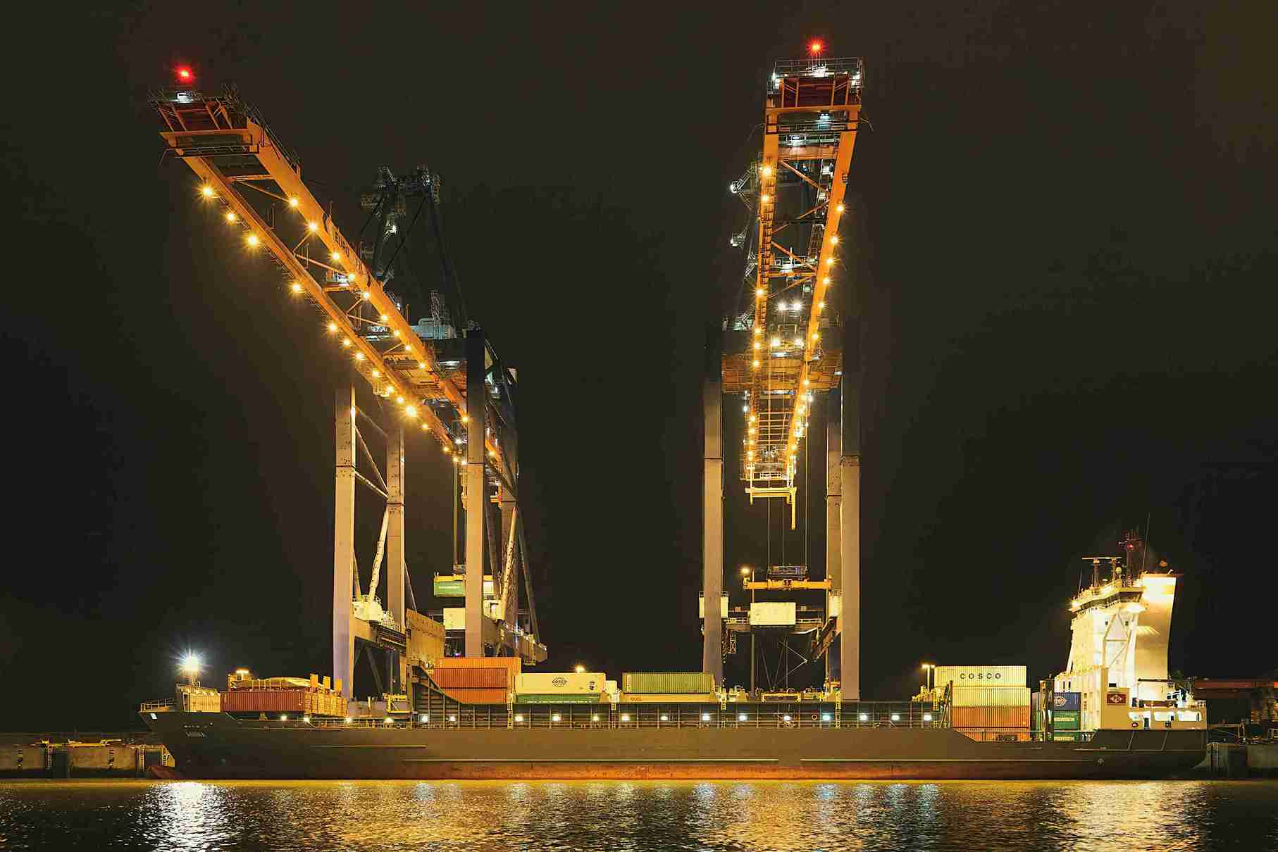 De haven van Rotterdam ’s nachts met een vrachtschip en containerkraan